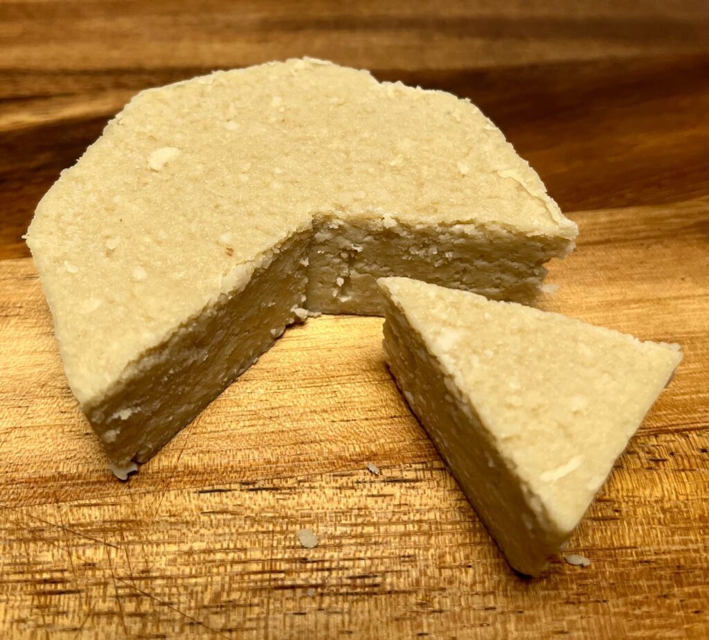 Cicioni vegan cheese by Casa del fermentino with a wedge cut out