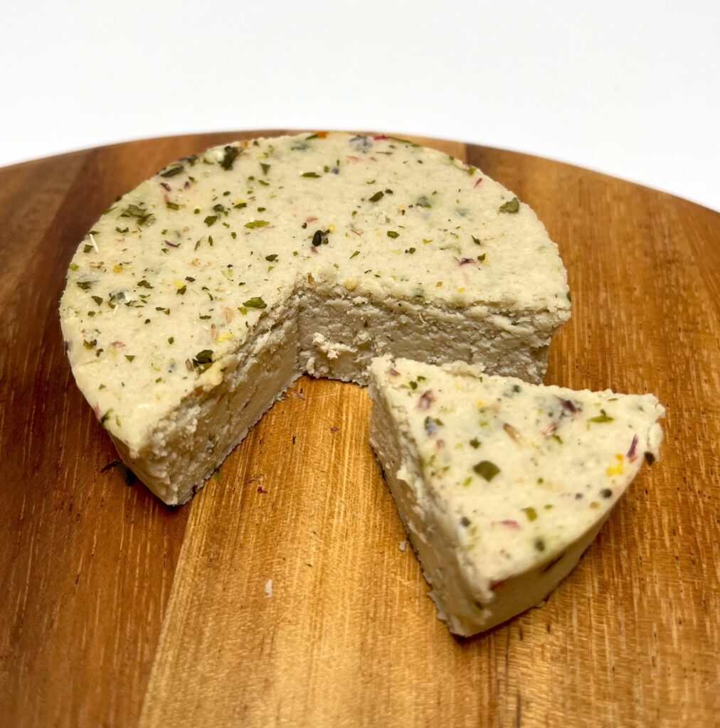 Ferme Herbs & Flowers vegan cheese by Casa del Fermentino with a wedge cut out