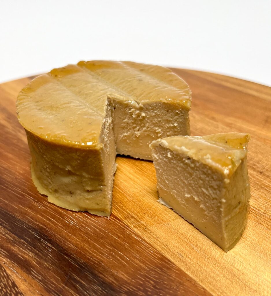 Smoked vegan cheese by Quevana with a wedge cut out