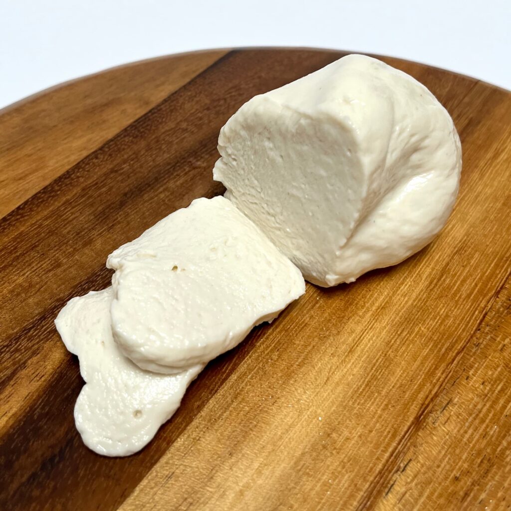 Mozzarella-alternative vegan cheese by Dreamfarm, partially sliced