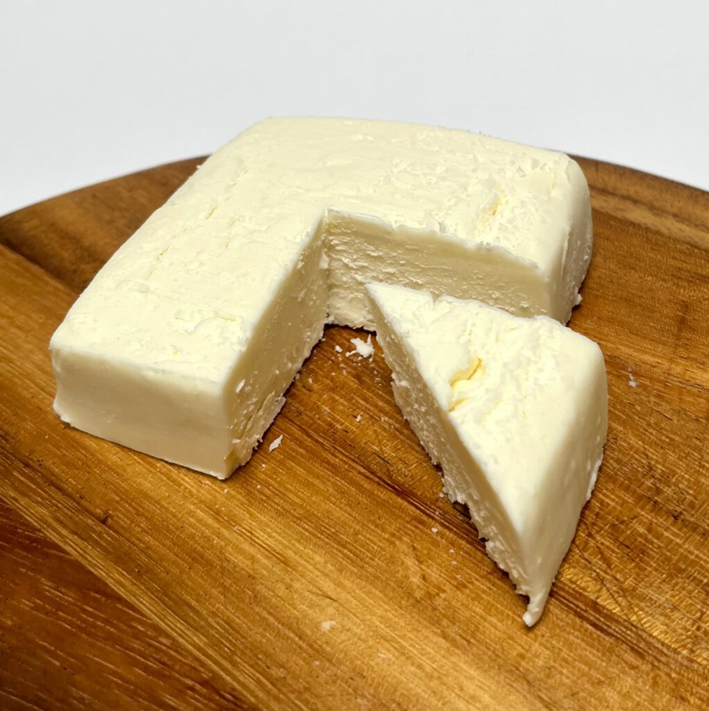 Sheese Greek Style vegan cheese by Bute Island with a wedge cut out