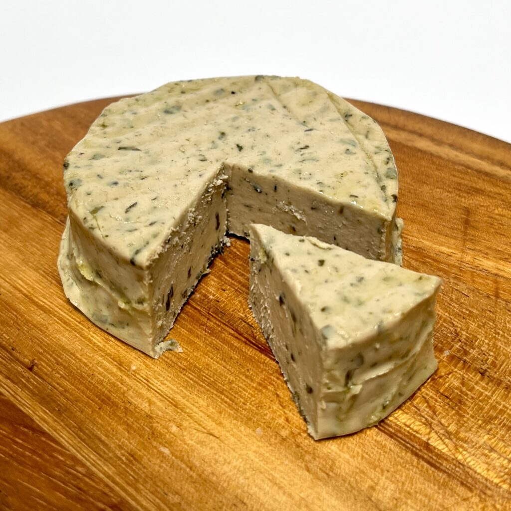 Wild Garlic vegan cheese by Nutty Artisan Foods with a wedge cut out