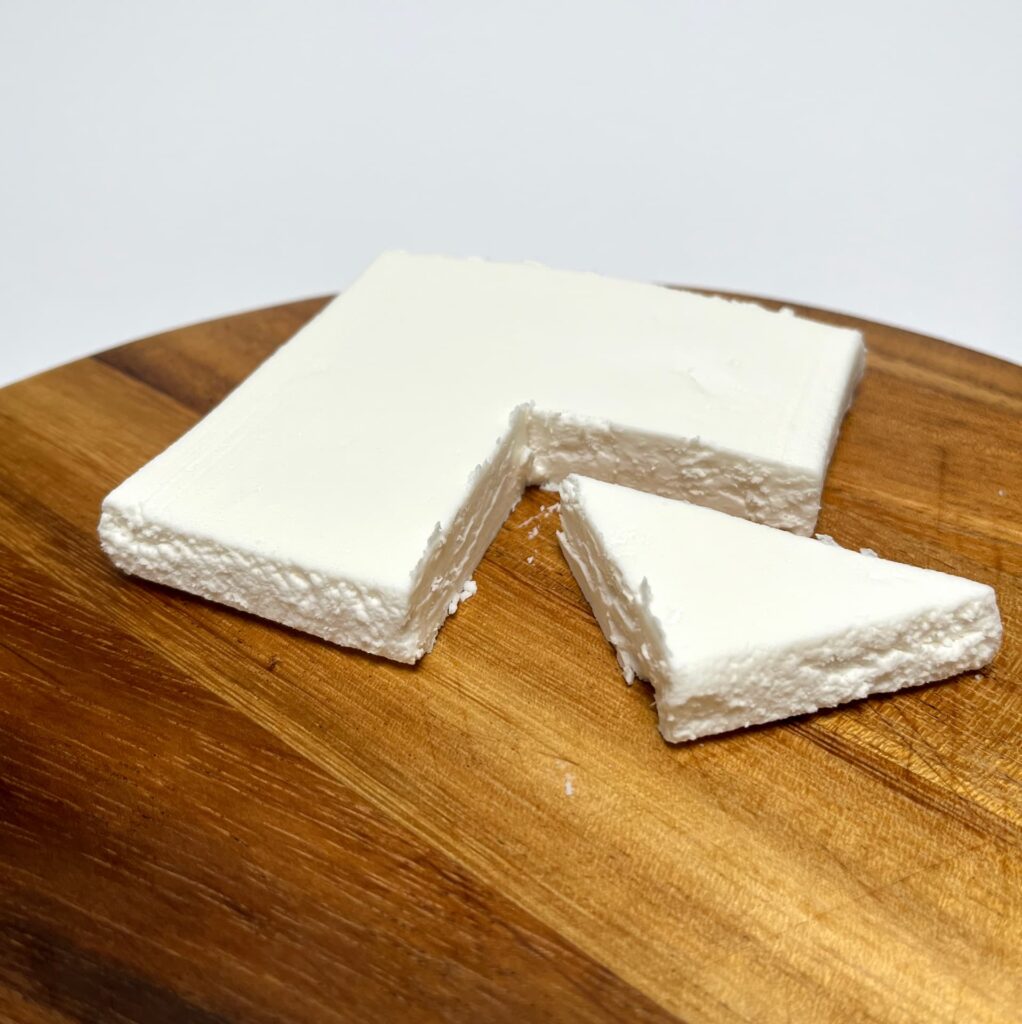 Plant-based White Slice vegan cheese by AH Terra with a wedge cut out